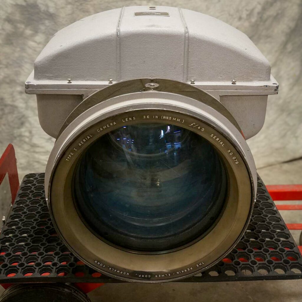 Front view of a Cold War Era aerial reconnaissance camera lens, displaying its large diameter and metal housing, used in U2 and SR 71 Blackbird spy planes, from Obtainium Science and Surplus.