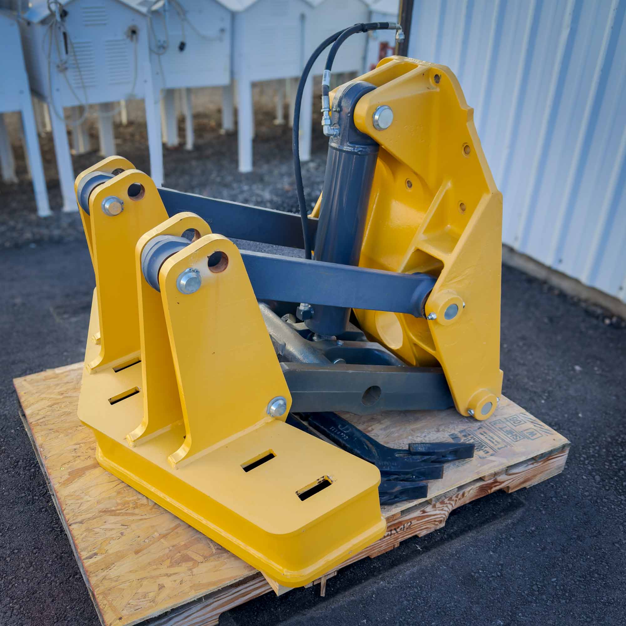 A perspective shot of the yellow Front Mount Scarifier for John Deere Motor Graders from Obtainium Science and Surplus, highlighting hydraulic connections.