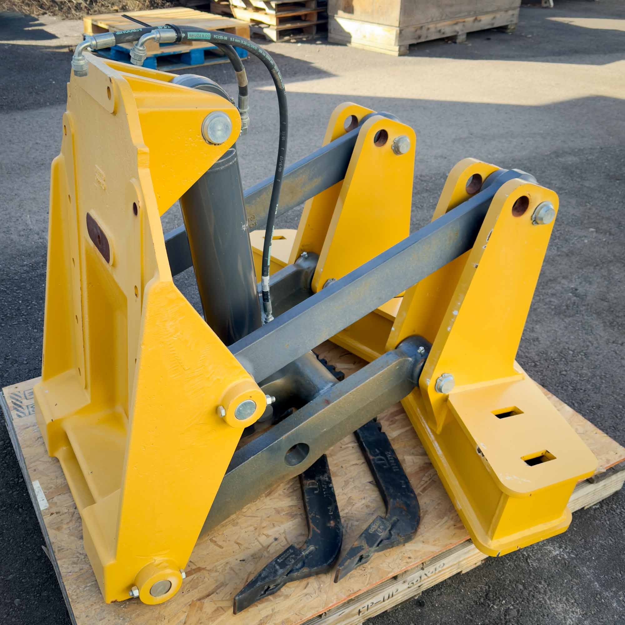 A side-angle view of the yellow Front Mount Scarifier for John Deere Motor Graders from Obtainium Science and Surplus, showing its reinforced steel arms and tines.