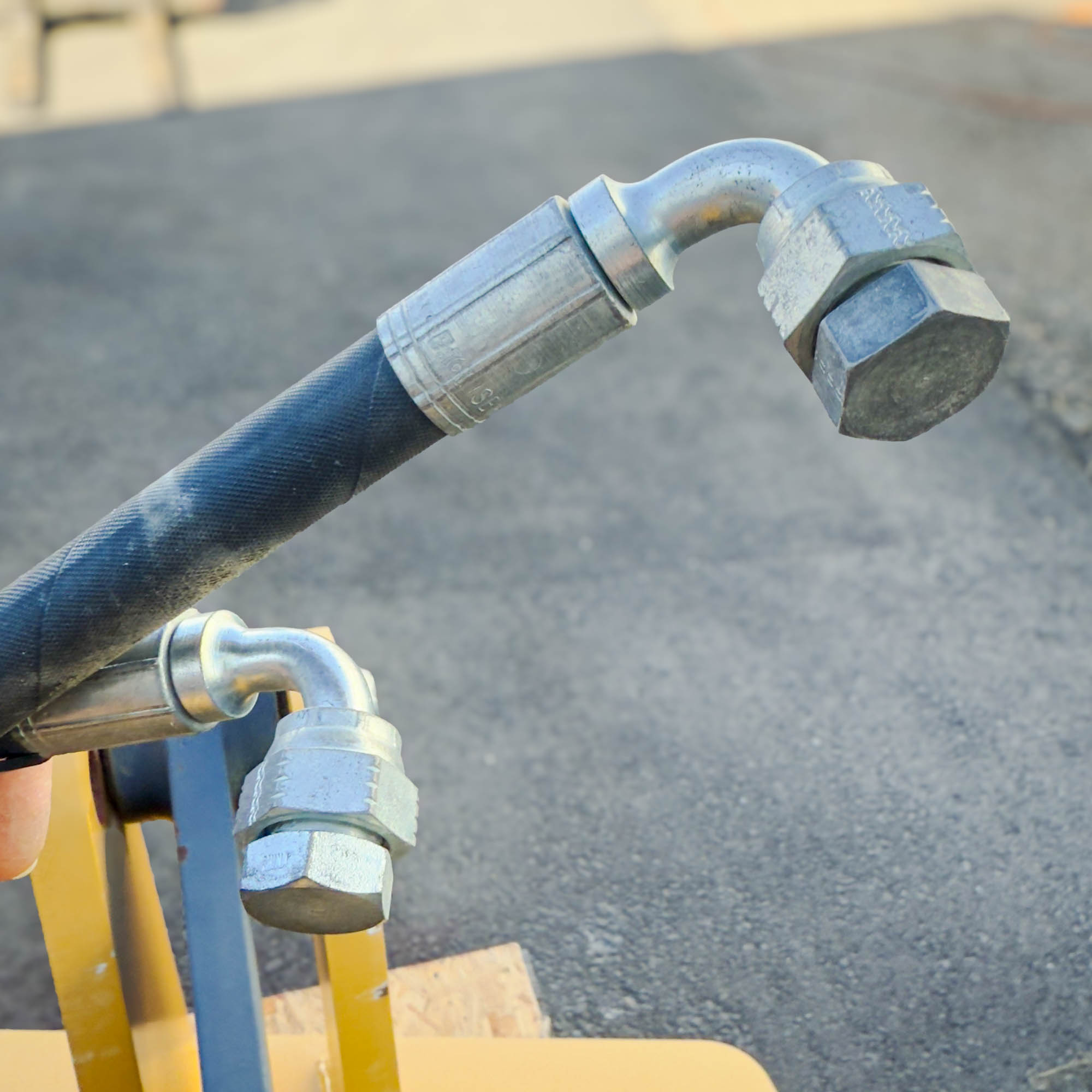 A close-up of hydraulic fittings and hoses from the Front Mount Scarifier for John Deere Motor Graders from Obtainium Science and Surplus, showing metal connectors.