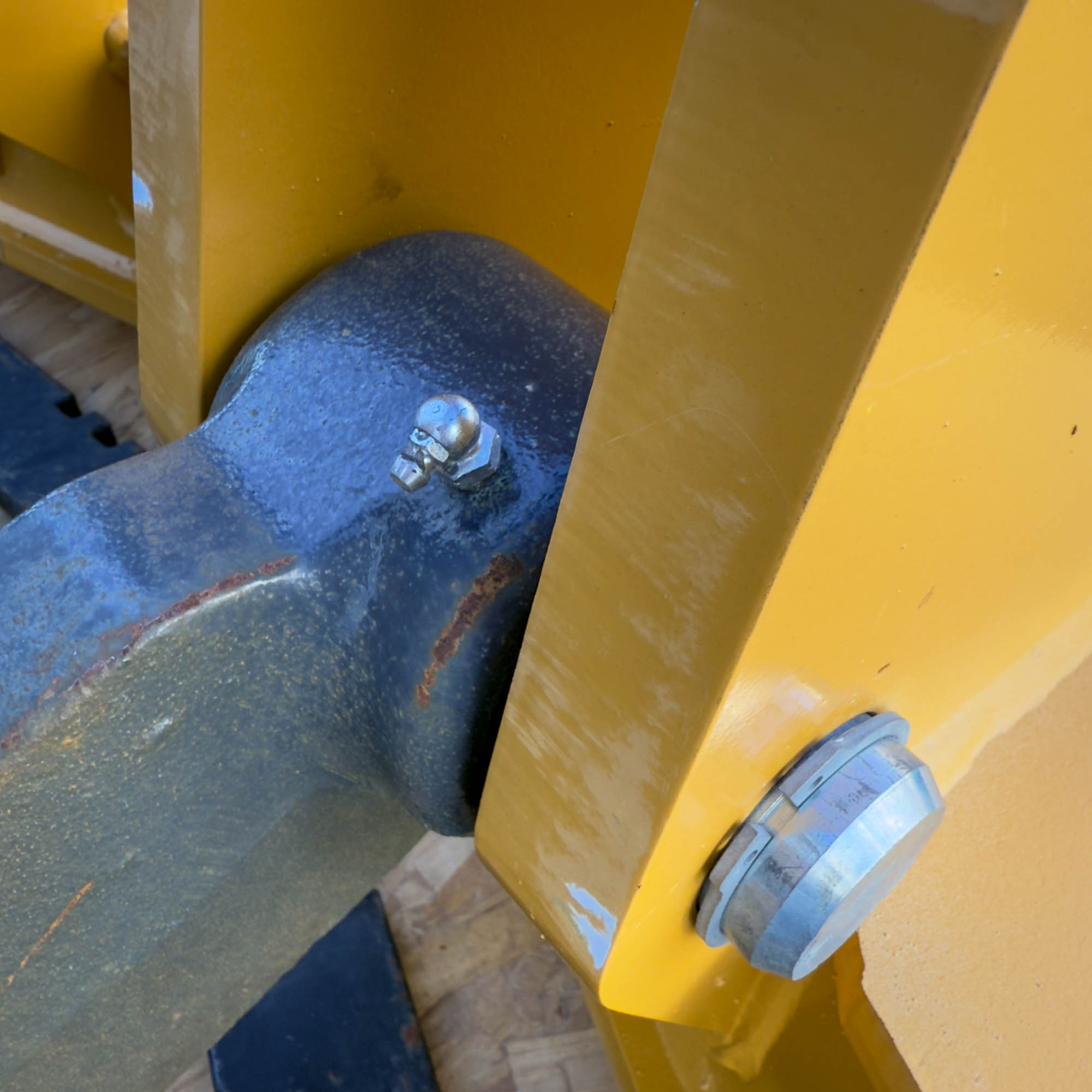 A close-up of a bolted joint on the yellow Front Mount Scarifier for John Deere Motor Graders from Obtainium Science and Surplus, displaying wear-resistant features.