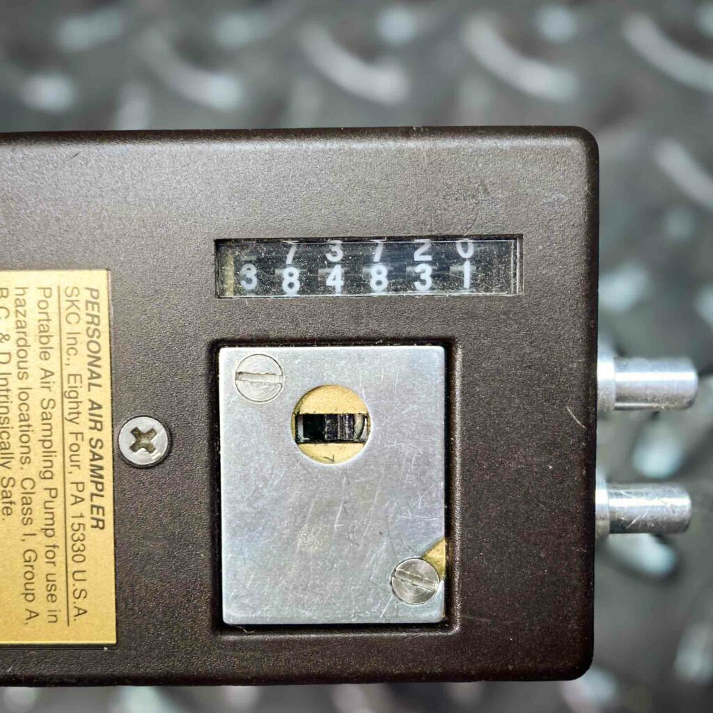 A detailed view of the SKC low-flow personal air sampler model 222 from Obtainium Science and Surplus, focusing on the counter display and adjustment dial on the device’s top. The numbers on the counter are visible, along with a small metal plate.